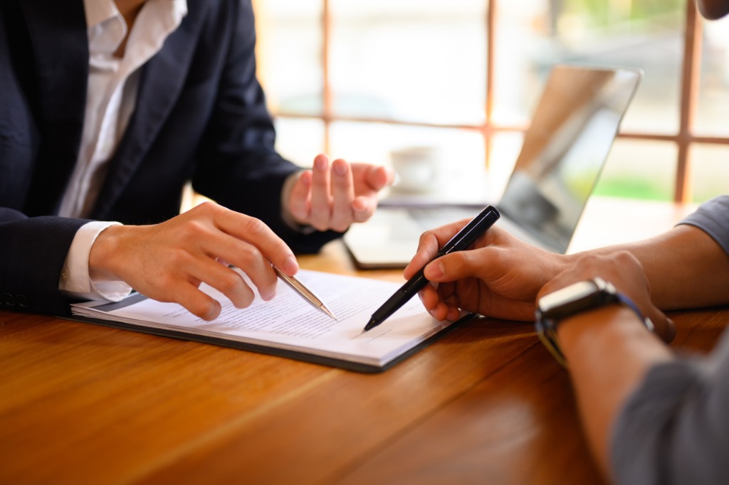 insurance agent pointing to contract for signature