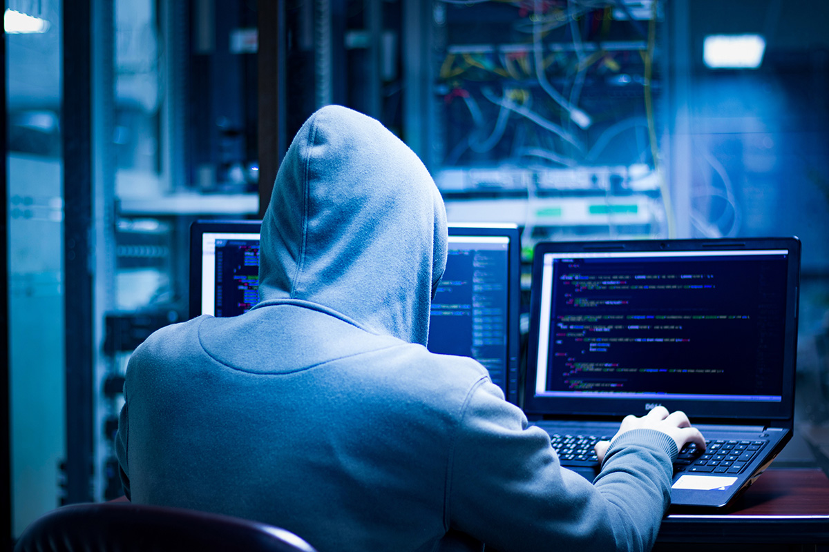 hacker on laptop in corporate server room