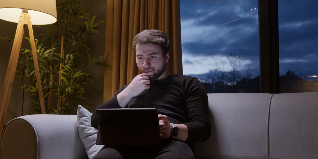 man using laptop at night on couch