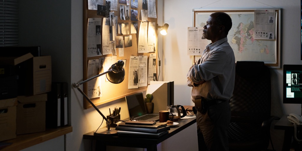 detective studying evidence in cold cases in dimly lit office